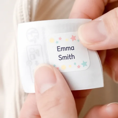 Fingers peeling a name label from its backing sheet
